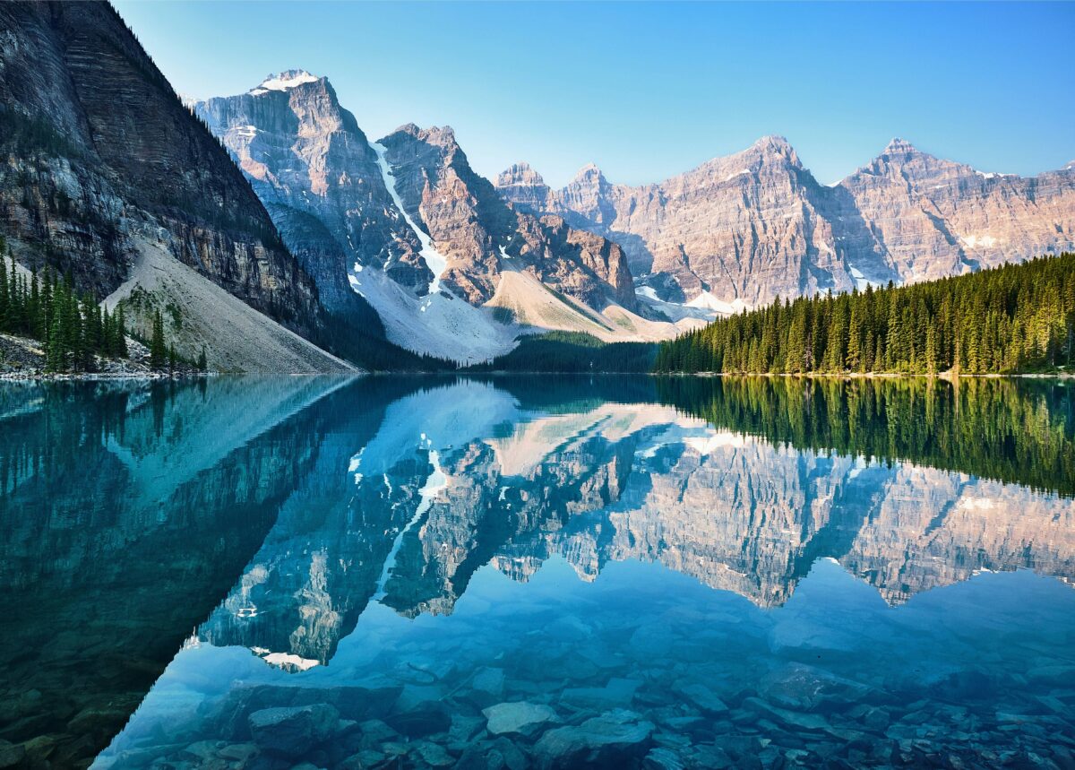 Crystal-clear Moraine Lake reflecting the Rocky Mountains and evergreen forest at sunrise in Banff National Park, Alberta, Canada.