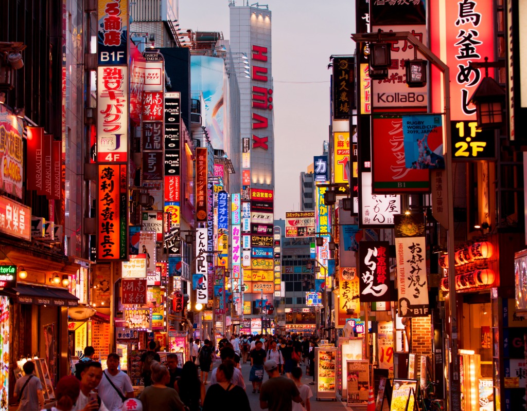 This image is a busy street in Japan with lots of fluorescent lights and people.