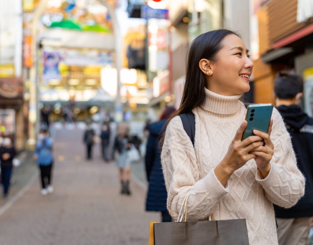 A lady in Japan using her phone through a secure internet connection, she is smiling and happy being able to use her phone