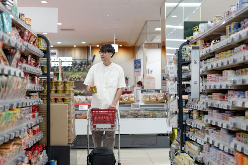 Shopper holding a cup of instant noodles in a Japanese supermarket aisle