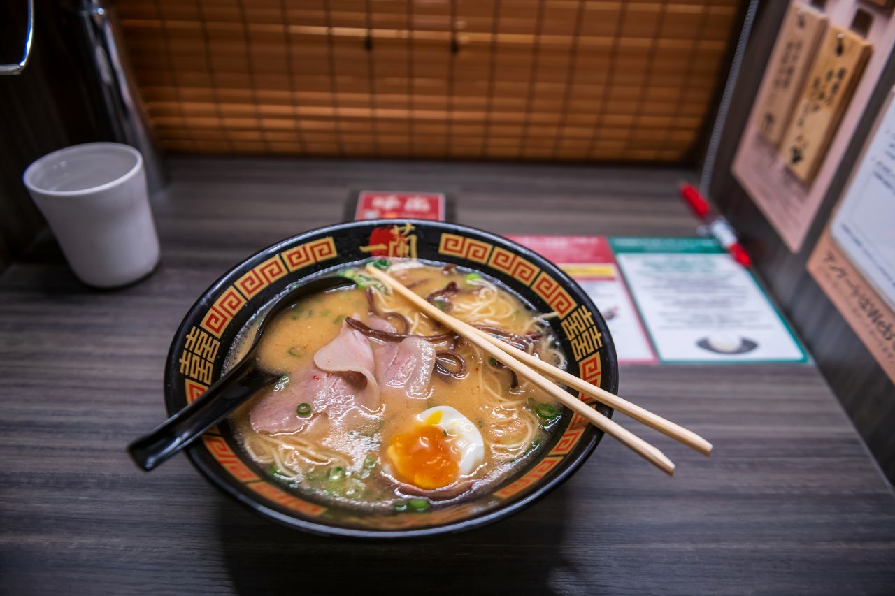 Bowl of tonkotsu ramen with pork, egg and chopsticks in a solo ramen booth in Japan