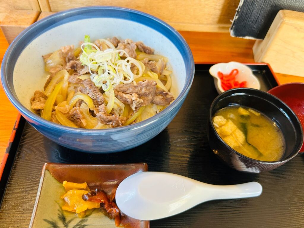 Gyudon beef bowl set with miso soup, pickled ginger and pickles on a lacquered tray