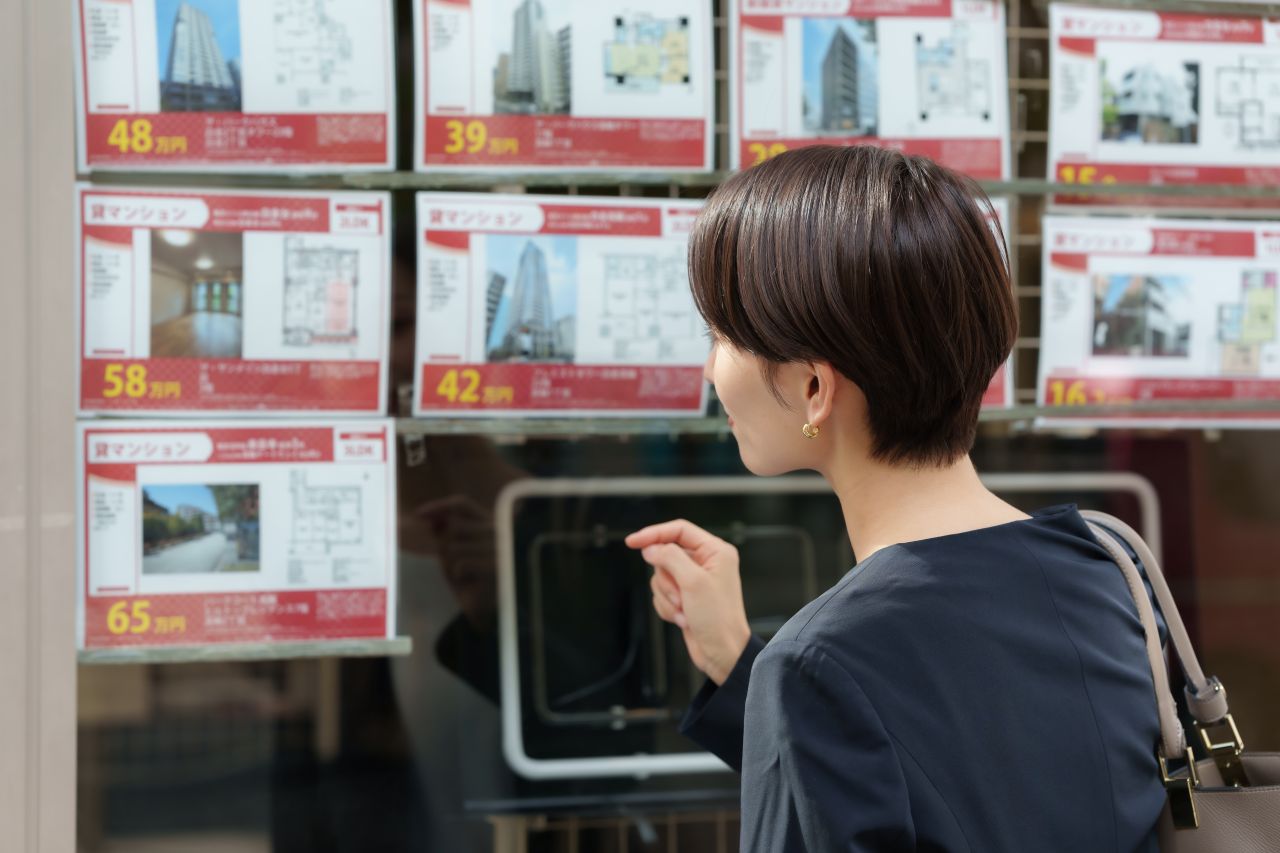 Person browsing rental listings in an estate agent’s window